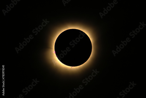 Total solar eclipse of April 8th 2024 with the sun peaking from behind the moon creating. a diamond ring effect. Red prominences and bright corona during totality