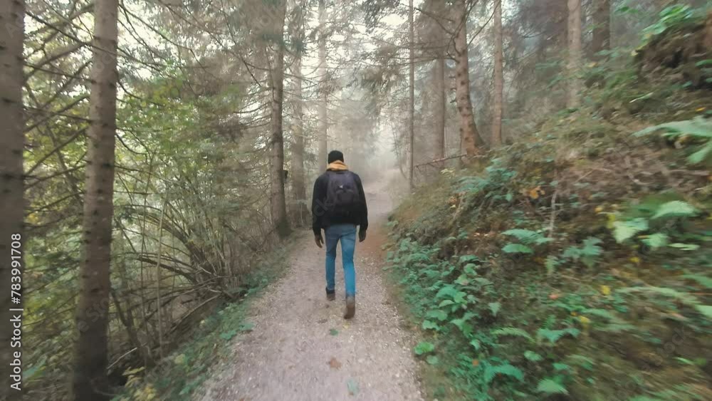 Man tourist with backpack comes up to the road direction sign and chooses the path in mountains wood Man tourist with backpack comes up to the road direction sign and chooses the path in mountains wood