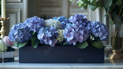   A table is adorned with a blue vase holding a collection of purple and blue flowers, accompanied by a book and a candle