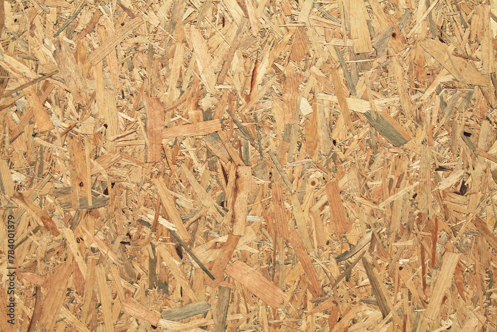 Wood (wooden) surface, texture, background. Building board made from pressed wood chips. A wall with a chaotic pattern created by press machines. Recyclable material technology. Fence, wall backdrop