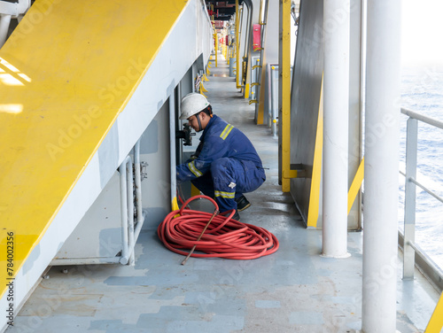 Seaman crew member of cargo vessel  equipped with personal protective equipment is preparing water hose for maintenance of main deck
