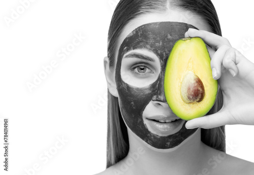 Beautiful smiling woman with clear skin holds a ripe avocado near her face. She applied the mask to her face. Cosmetological skin care