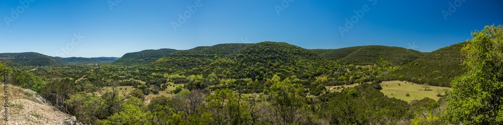 Green hills with forest valley and clear blue sky