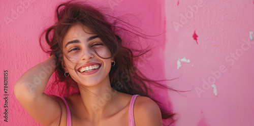 Junge hübsche Frau lächelt, Mädchen mit rosa Oberteil vor einer rosa Wand photo