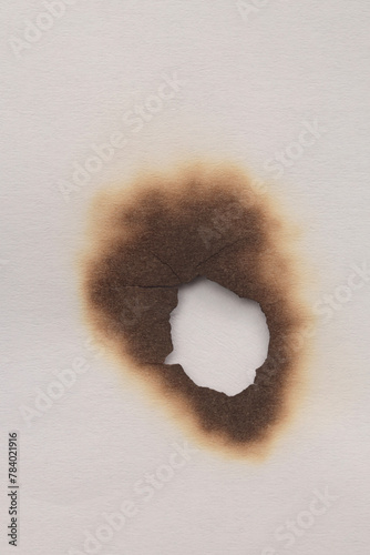 Empty old torn burned grunge pieces texture cardboard paper hole on beige white background.