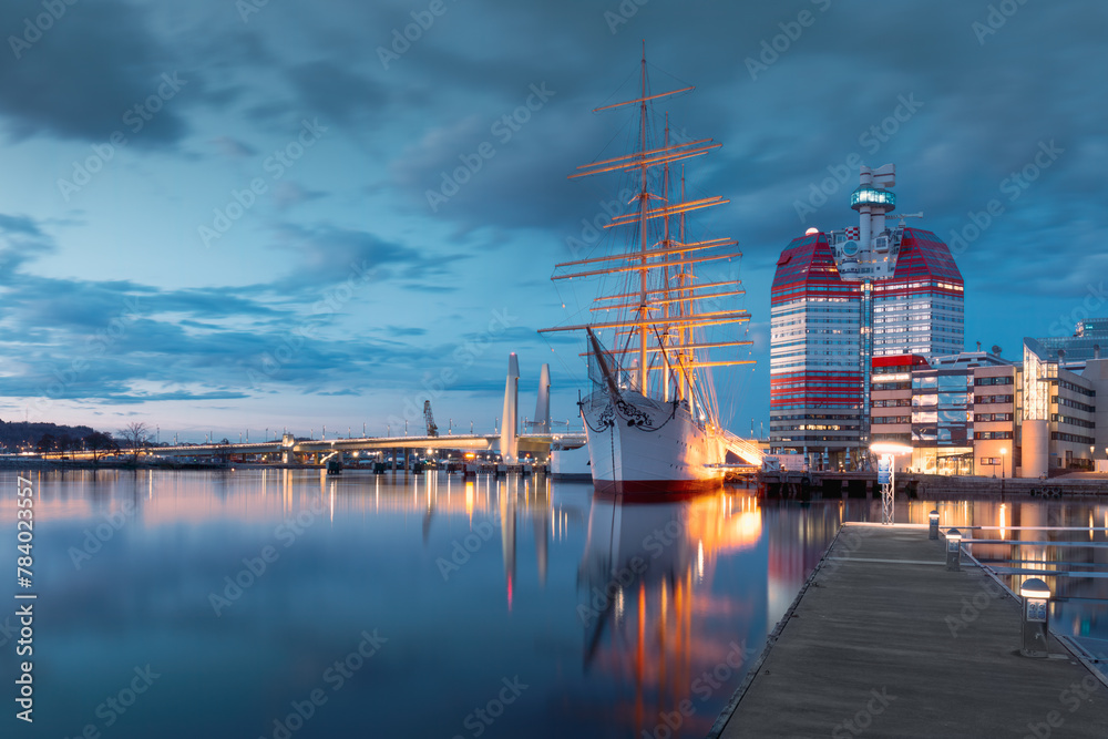 Waterfront with historic sailing ship in Gothenburg, the iconic Lilla Bommen building with night lights. Concept of maritime heritage and travel. Gothenburg, Sweden