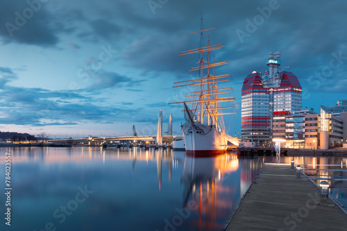 Waterfront with historic sailing ship in Gothenburg, the iconic Lilla Bommen building with night lights. Concept of maritime heritage and travel. Gothenburg, Sweden photo