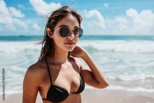 A woman at a beach wearing a black bikini.