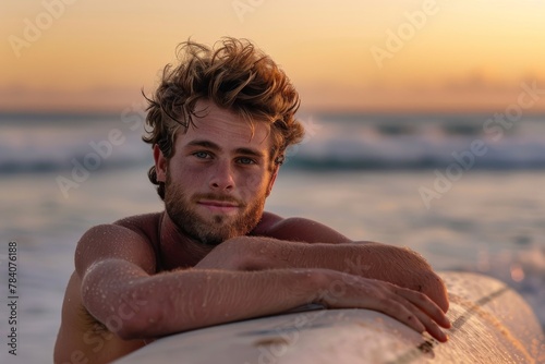 A sun-kissed surfer rests on his board  with a beautiful sunset backdrop at the beach