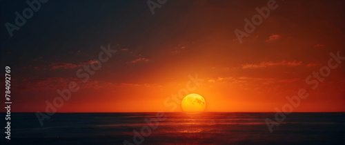 The image depicts an oversized sun setting over the ocean's horizon, with a vibrant play of orange and red hues piercing through scattered clouds © JohnTheArtist