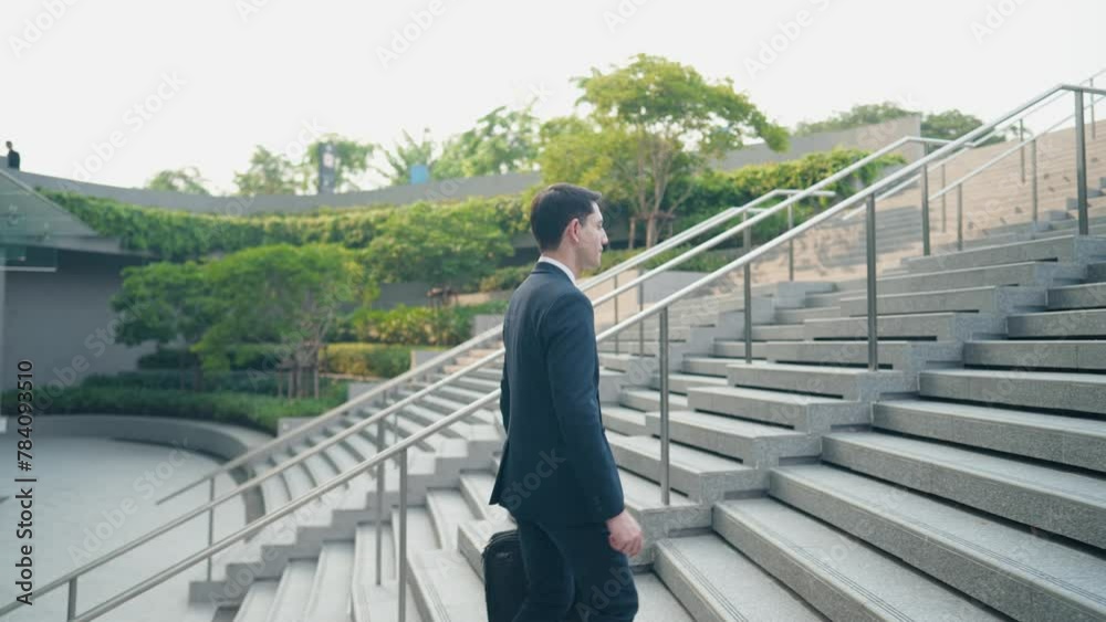 Side view of handsome businessman walking up the stairs to work, outdoor urban city, working man holding business bag, urban commuter, salary man walking to work, work profession, first day at work Side view of handsome businessman walking up the stairs to work, outdoor urban city, working man holding business bag, urban commuter, salary man walking to work, work profession, first day at work