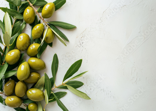 Green olives on a branch with leaves on white background, copy space for text. Flat lay, top view, lifestyle banner