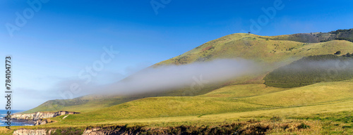 Panorama of rolling hills of grass with clouds, fog © Mark