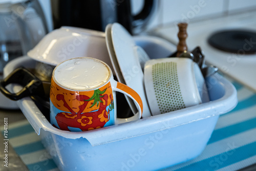Fotografija Clean dishes - cups, plates, bowls, cooking pot are getting dry in the broken blue washbowl at the camping kitchen