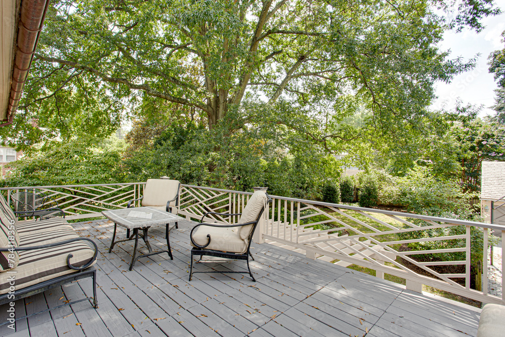 Cozy Outdoor Terrace Deck with Furniture Under a Large Tree Overlooking Lawn