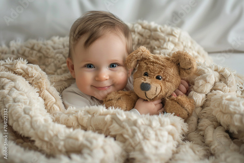 Adorable baby sitting in a pile of soft blankets, cuddling a plush toy.