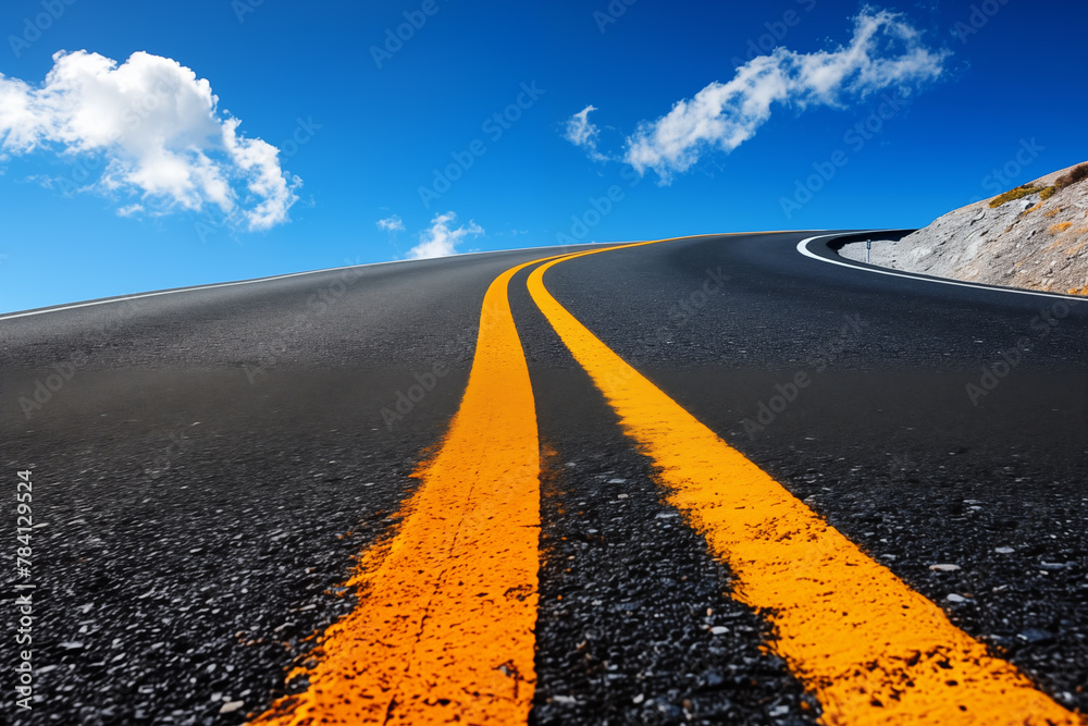 Naklejka premium Dramatic view of a curvy mountain road with vivid yellow stripes