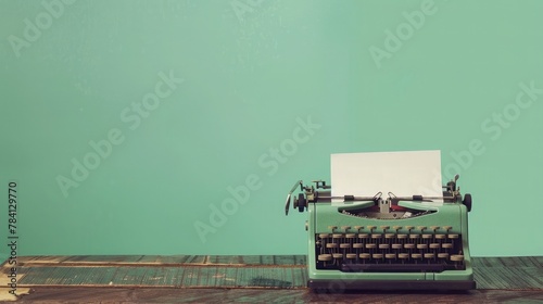 Retro old typewriter with paper on wooden table front mint green background photo