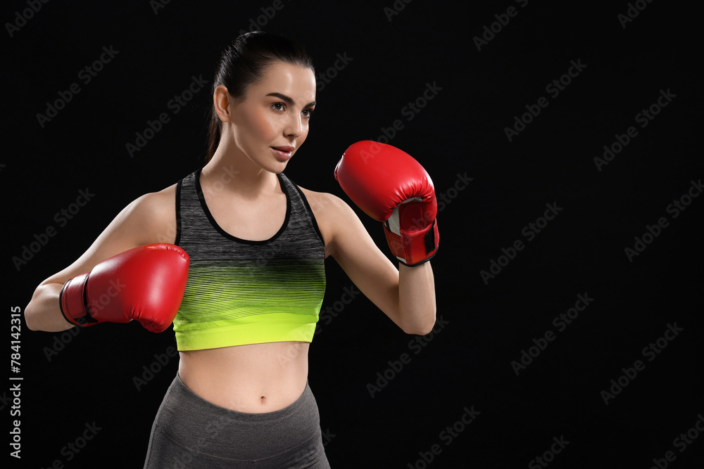 Beautiful woman in boxing gloves training on black background. Space for text Beautiful woman in boxing gloves training on black background. Space for text