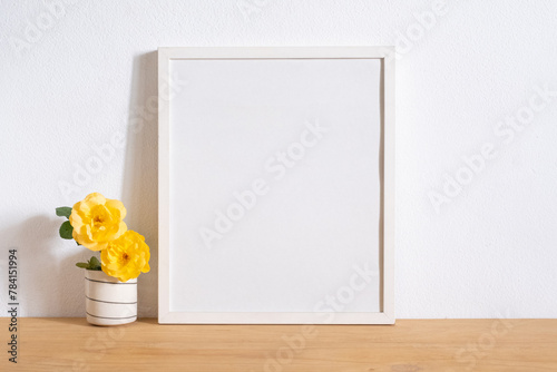 blank white frame with yellow rose flowers on table