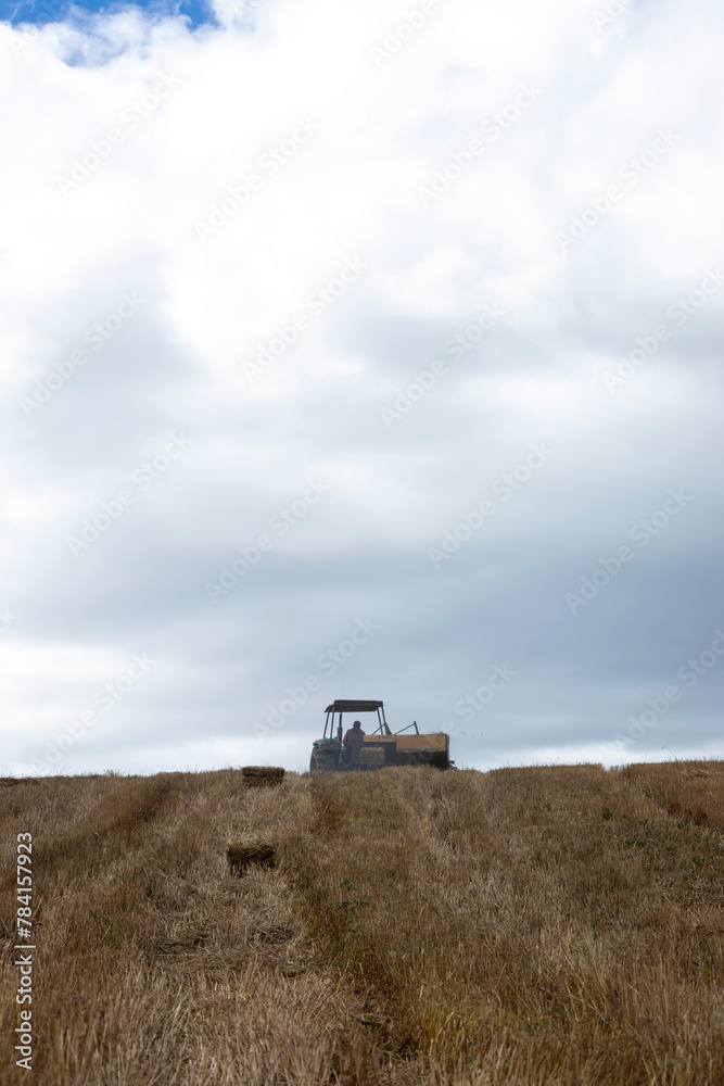 Tractor with a hay baling machine on the horizon of a hill in the Andes mountains