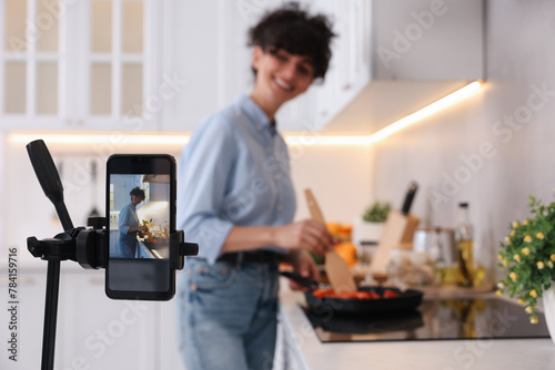 Food blogger cooking while recording video in kitchen  focus on smartphone