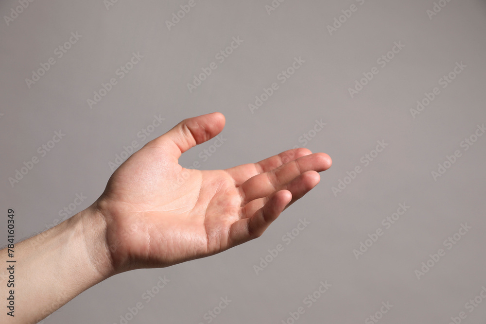 Man holding something in hand on grey background, closeup. Space for text Man holding something in hand on grey background, closeup. Space for text