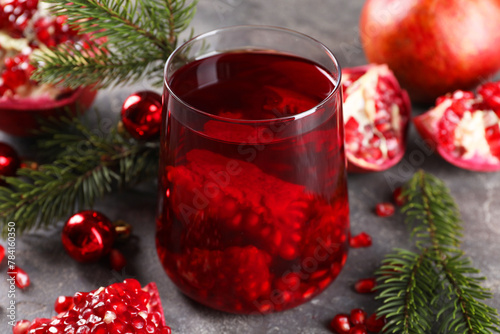 Aromatic Sangria drink in glass, Christmas decor and pomegranate grains on grey table