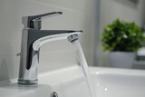 Water Flowing from Modern Faucet into Sink with Plant Background