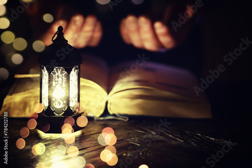 Ramadan Kareem background. Ornamental Arabic lantern glowing and the holy book of Quran. photo