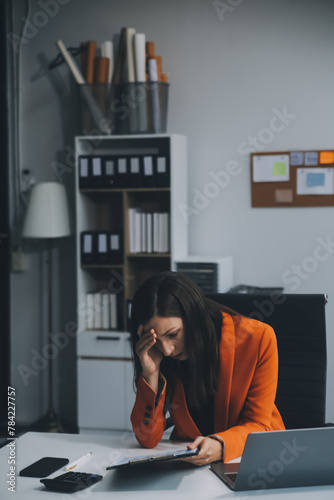 Portrait of tired young business Asian woman work with documents tax laptop computer in office. Sad, unhappy, Worried, Depression, or employee life stress concept