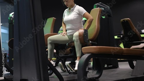 Asian woman with beautiful face is excited to train her glutes muscles with a gym machine. photo