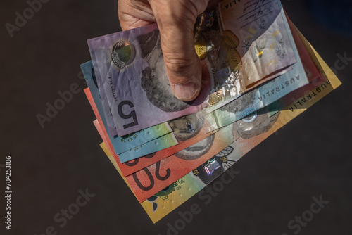 Close-up of Australian dollar banknotes handheld in the sun. photo