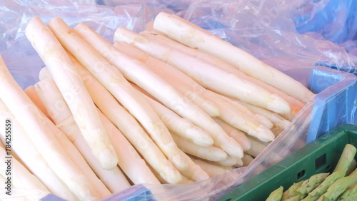 Male hands pick fresh white spring asparagus at a farmer's market counter in spring.