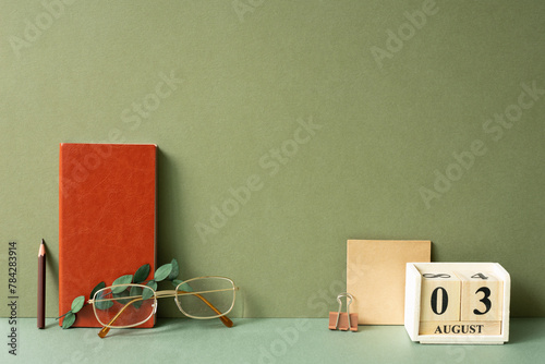 Obraz na płótnie Workspace diary note, calendar, notepad, clip, pencil, eyeglasses, eucalyptus leaf on green desk. khaki wall background w salonie