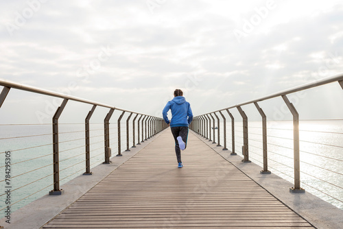 Rear view of a fit woman running seaside on a promenade