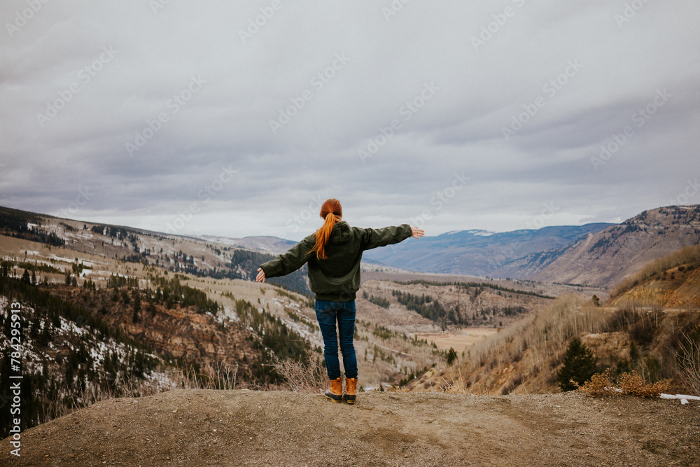 Woman outstretches arms looking out at Vail Colorado Rocky Mountains