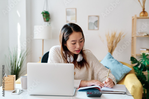 Woman seated at desk, working on laptop photo