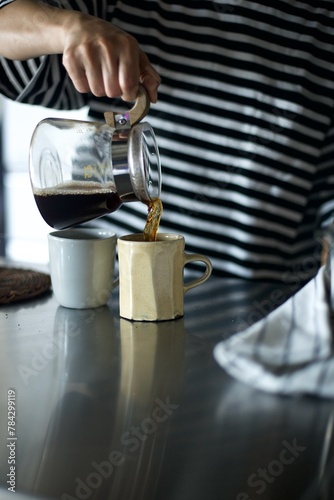 ドリップしたコーヒーをカップに注ぐところ © Takahiro