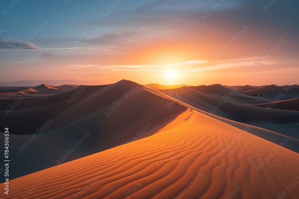 The sun dips below the horizon, casting a warm glow over a vast sand dune in the desert