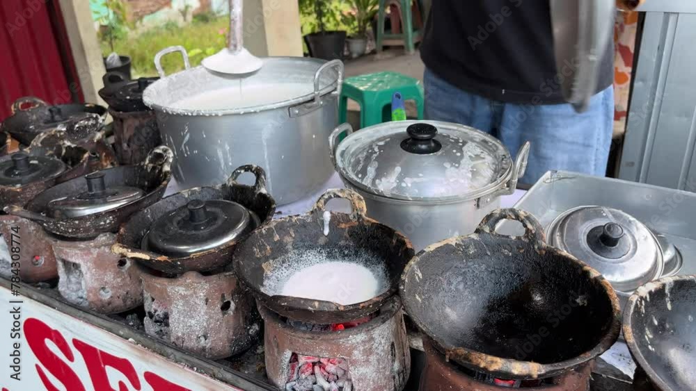 The process of making traditional dessert named Serabi made from rice flour and coconut milk by an old man with charcoal stove The process of making traditional dessert named Serabi made from rice flour and coconut milk by an old man with charcoal stove