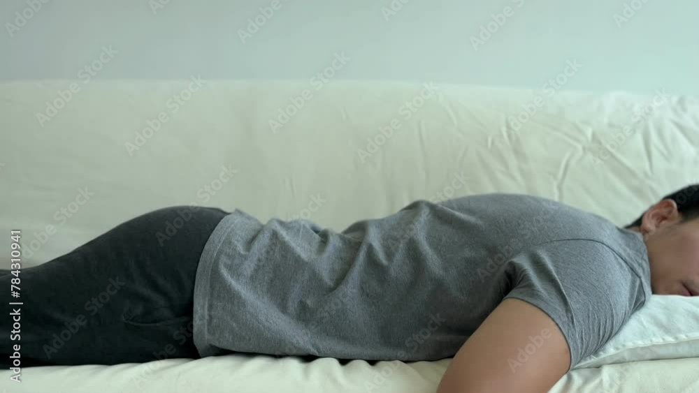 Asian man lie and rest on the sofa taking a day nap as he tired. Asian man lie and rest on the sofa taking a day nap as he tired.