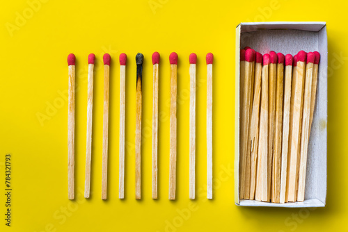 Success, defeat, achievement. The concept of happiness. Matches on a yellow background. Burnt dark match among normal matches. Burning match fire to its neighbors, a metaphor for ideas and inspiration
