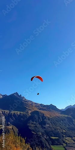 Paraglider against mountains, close up, from below, clear blue sky 