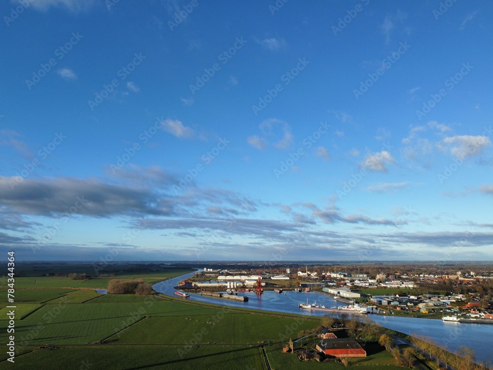 Aerial shot of a canal flowing along a small town under the blue sky Aerial shot of a canal flowing along a small town under the blue sky