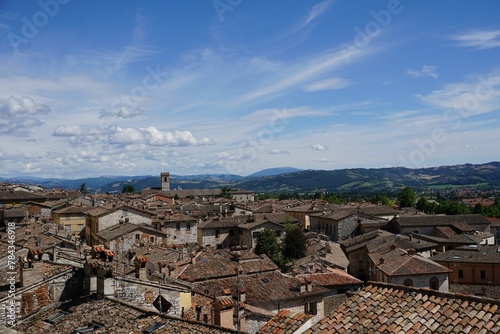 Aerial view of buildings in beautiful medieval Gubbio town in Italy under blue cloudy sky