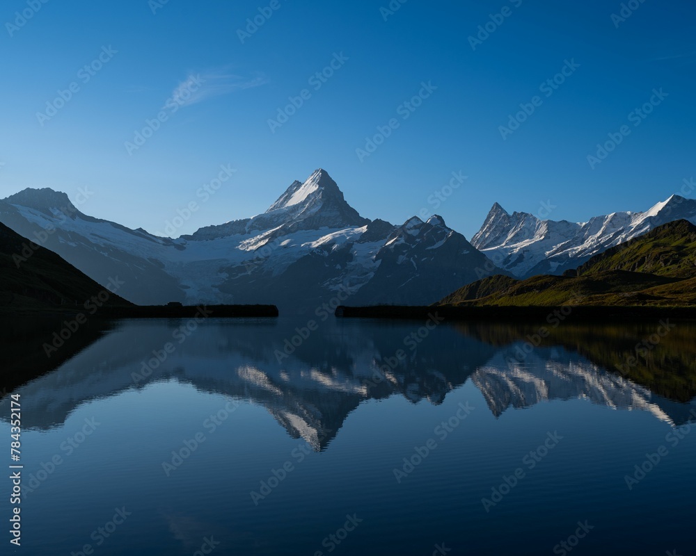 Fototapeta premium Landscape shot of a lake reflecting the beautiful peaks in the Swiss alps under the clear blue sky