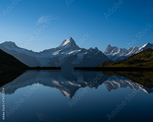 Landscape shot of a lake reflecting the beautiful peaks in the Swiss alps under the clear blue sky