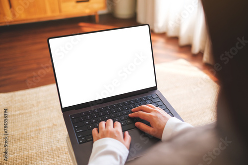 Mockup image of a woman working and typing on laptop computer with blank white desktop screen at home