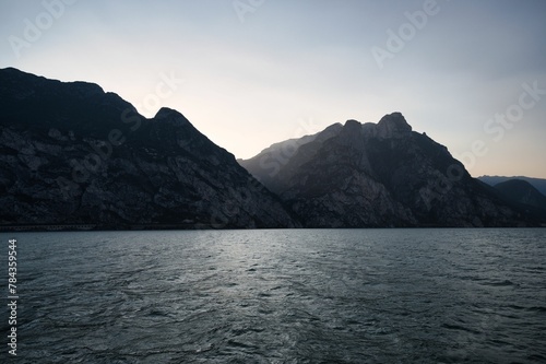 Landscape of lake Garda surrounded by hills under a blue sky and sunlight in Italy